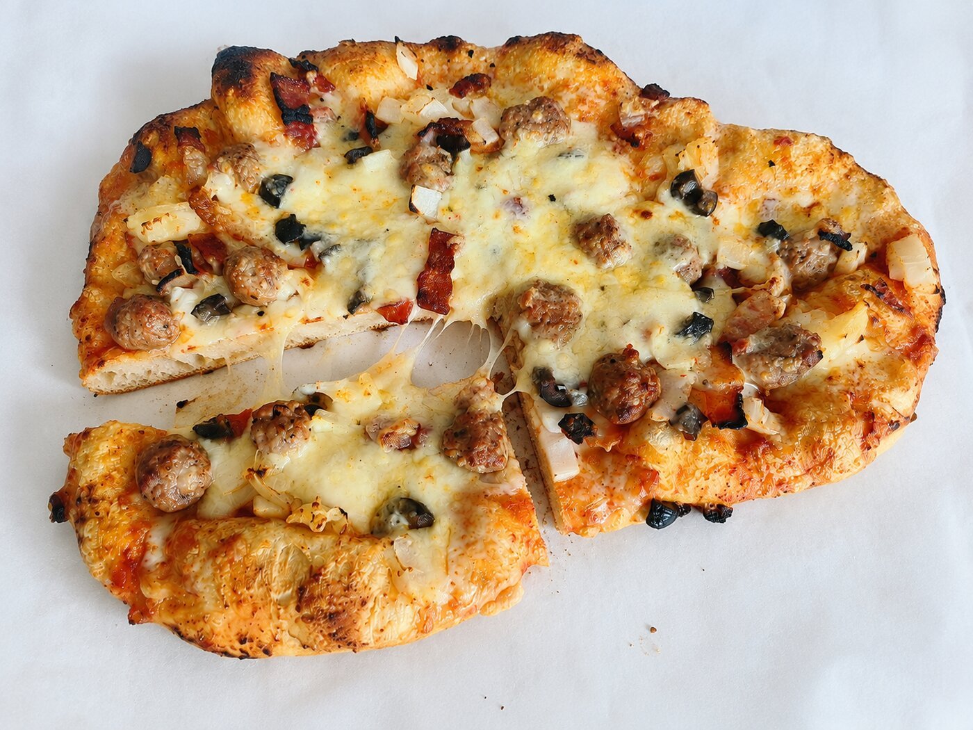 A finished rustic homemade pizza cut into slices, with an irregular hand-stretched crust