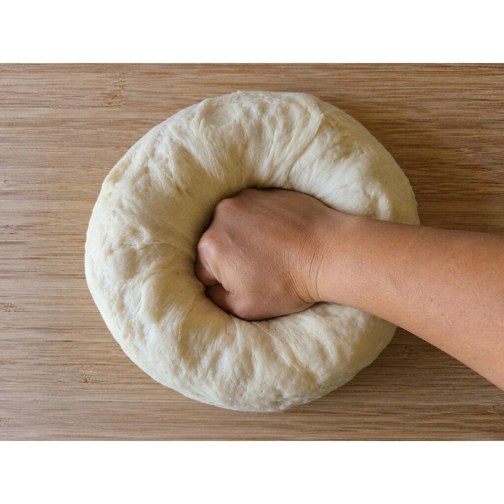 Punching down the risen pizza dough by hand